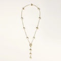 Gold-plated lariat necklace with baroque pearls and textured caps on cream background, showing adjustable Y-shaped design.