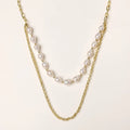 Layered gold chain necklace with organic baroque freshwater pearls and adjustable length on cream background
